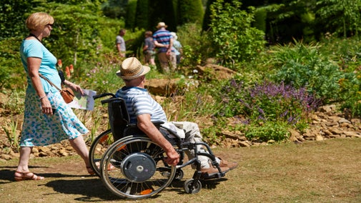 a visitor in a wheelchair enjoys the gardens at Hidcote